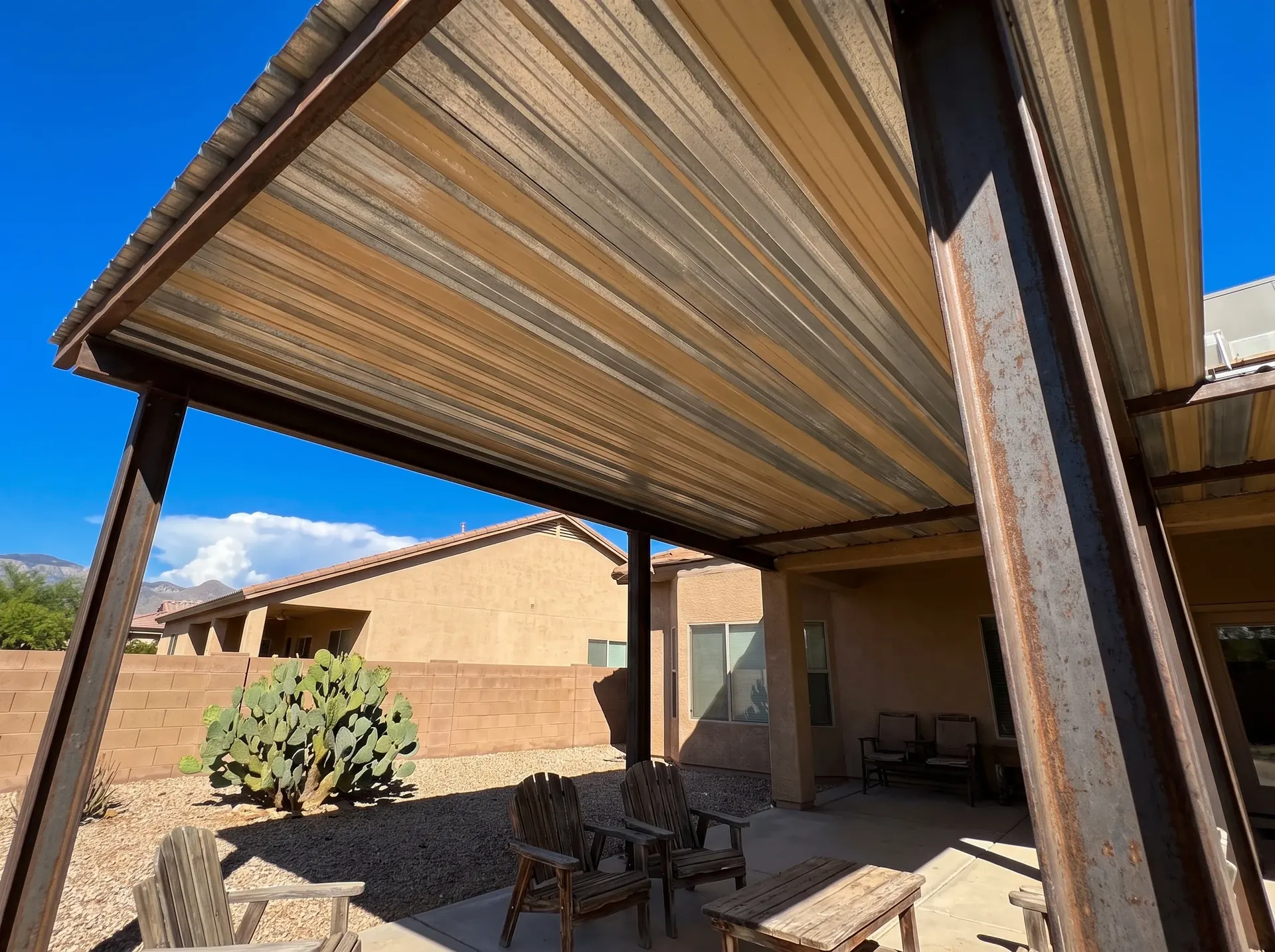 Metal panel roof over a shaded patio ramada beside a desert home